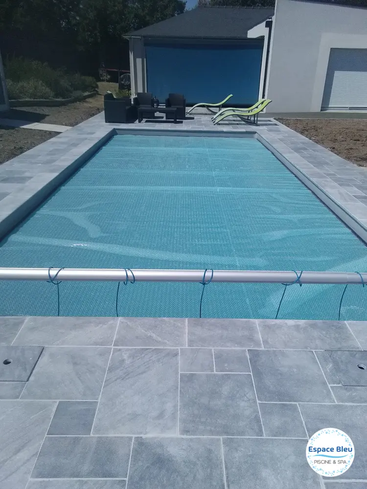 Piscine avec couverture à lames et plage en dalles grises