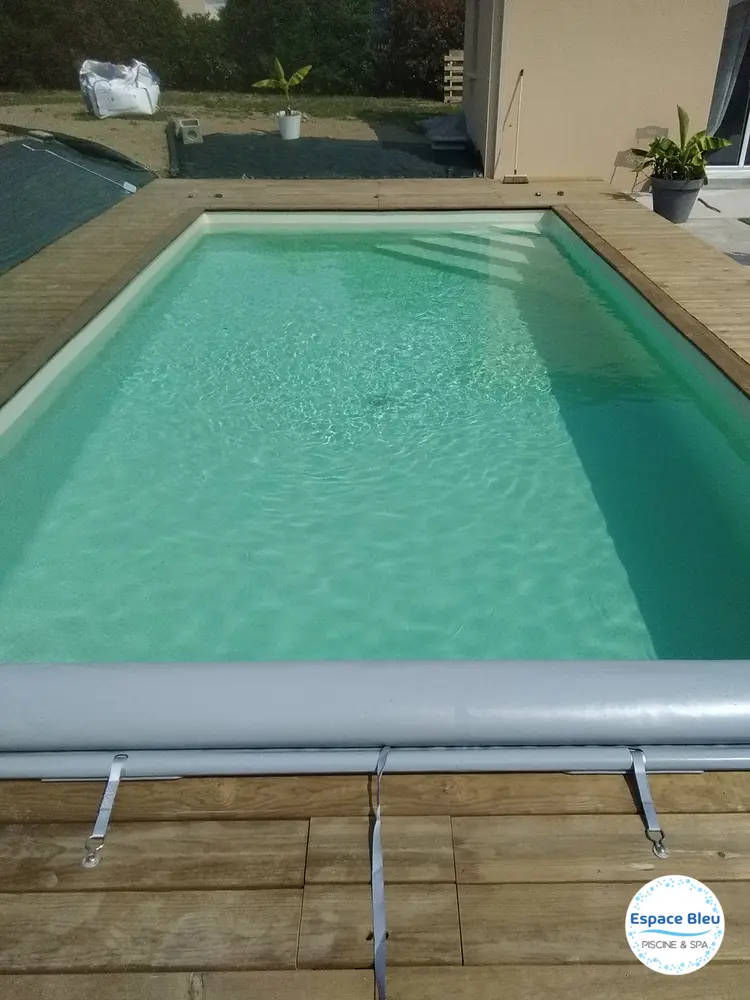 Piscine à eau turquoise avec volet roulant et terrasse bois