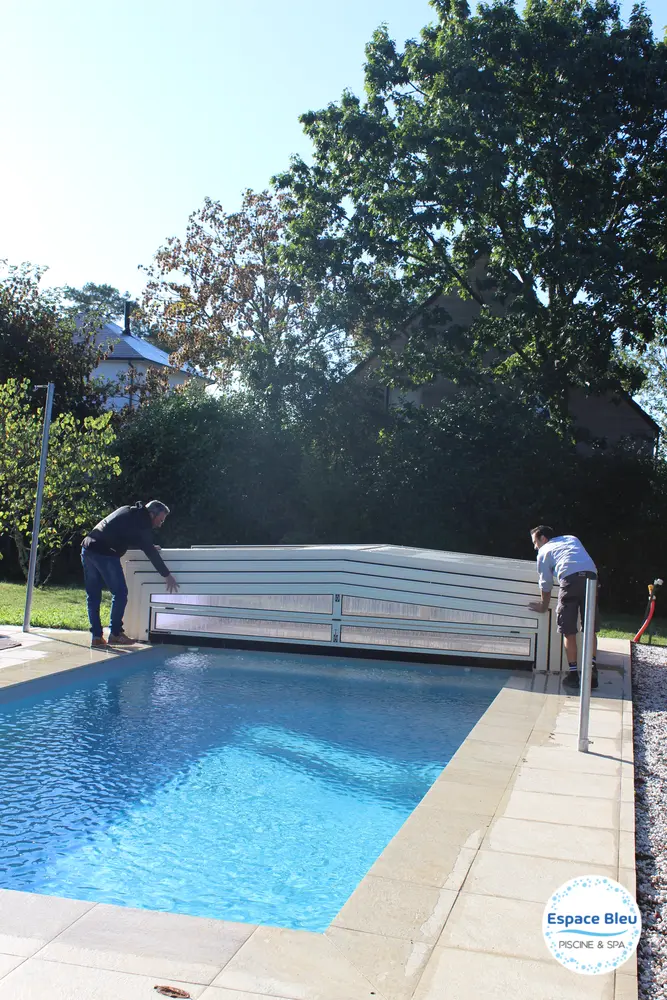 Piscine à eau bleue avec abri bas fermé et jardin