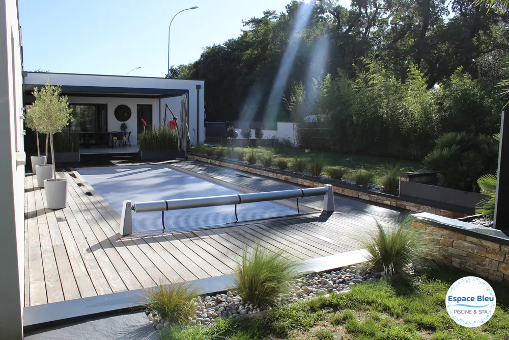 Piscine avec volet dans un jardin paysager