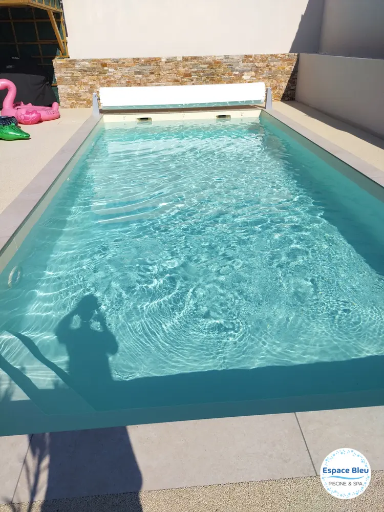 Piscine rectangulaire avec volet enroulé et margelle beige