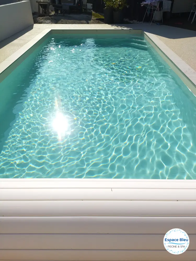 Piscine à eau turquoise avec volet blanc en bout de bassin