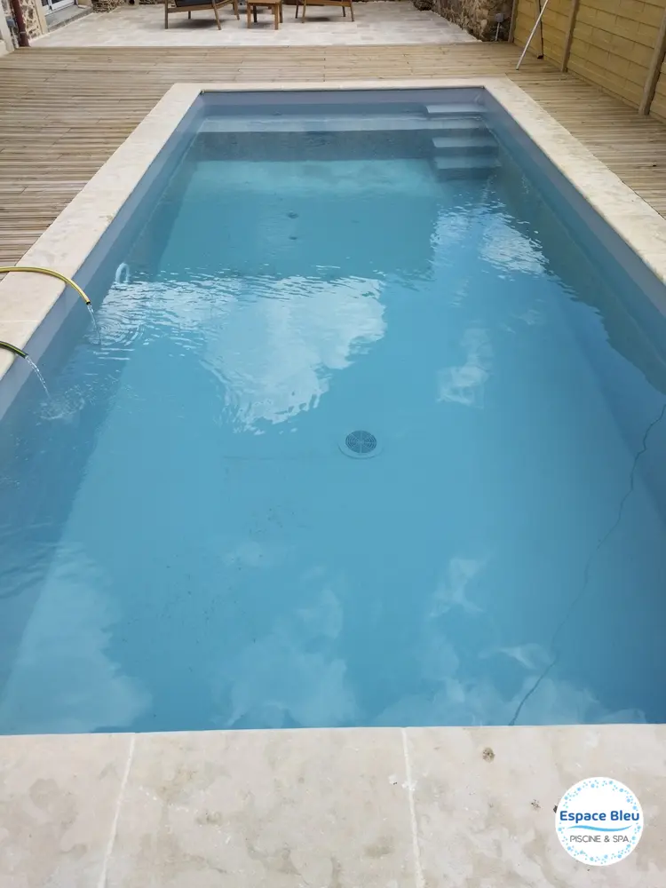 Piscine à eau bleue claire avec plage en pierre
