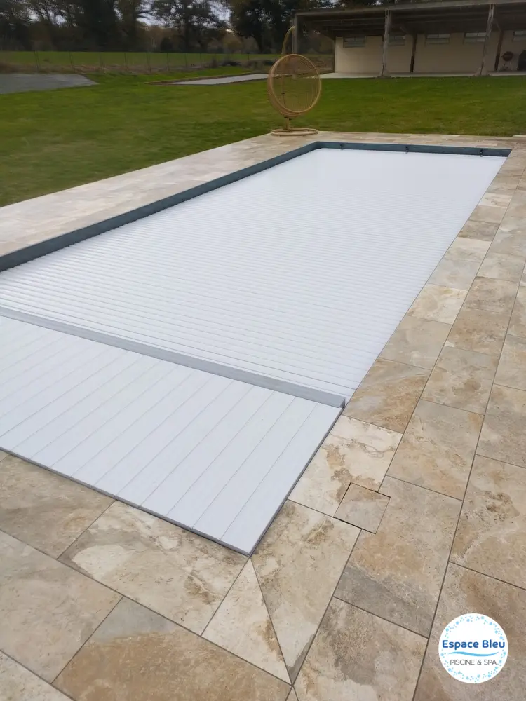 Volet blanc fermé sur piscine entourée de pelouse