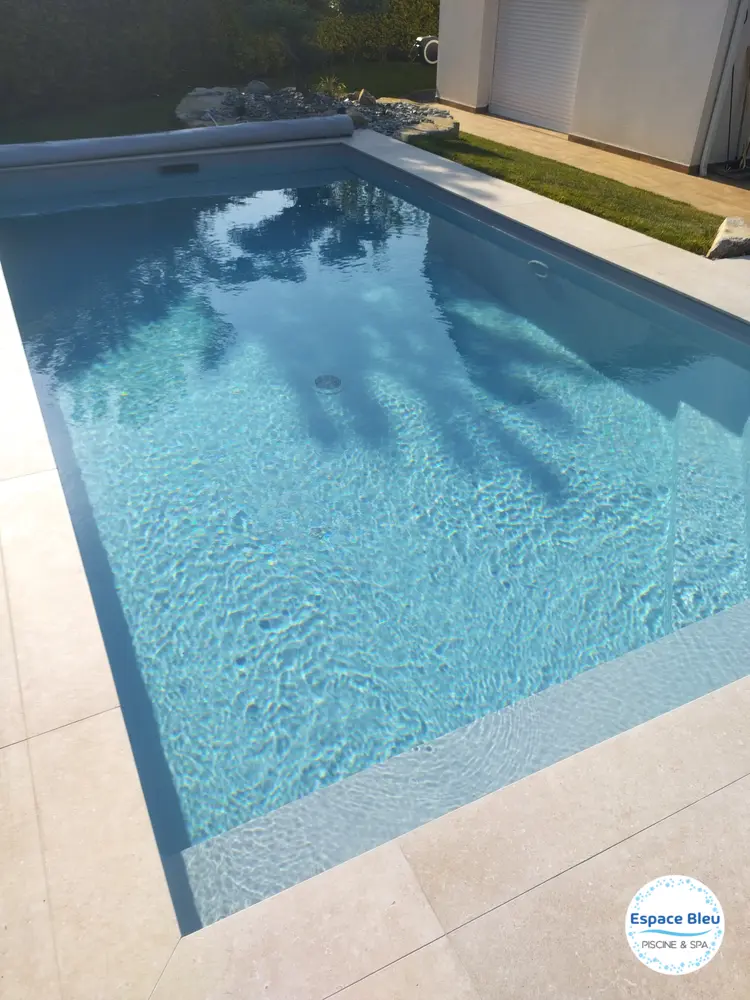 Piscine à eau bleue et plage en pierre, vue d’ensemble