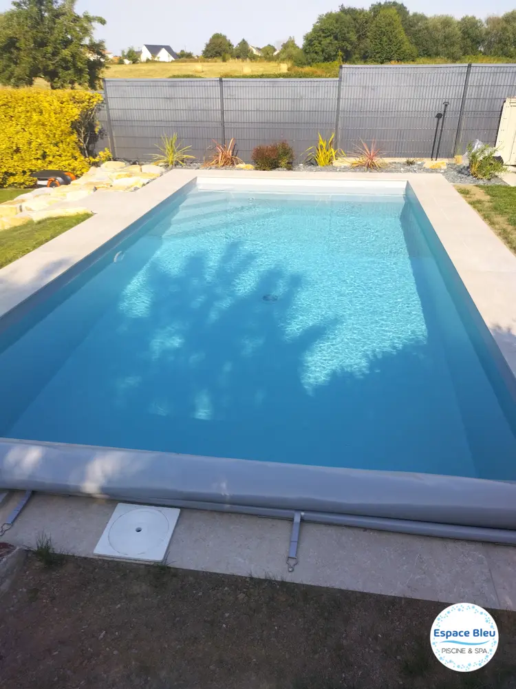 Piscine bleue avec volet enroulé dans un jardin